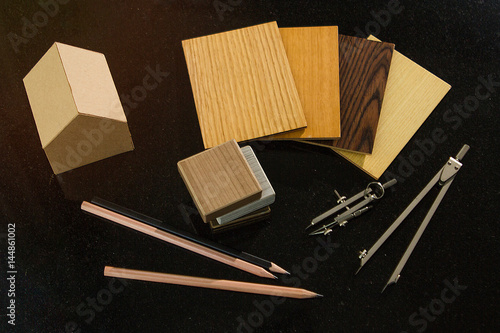 achitect samply materials for home design and construction concept with copy space.  pencils and protracters, house and wood grain samples with black background. photo