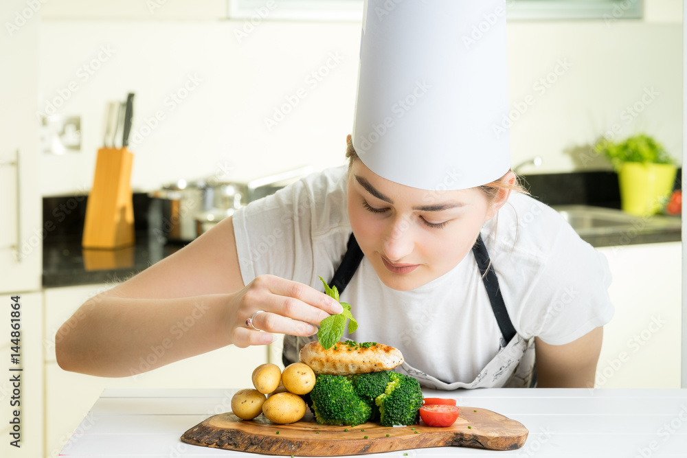 concentrated female chef garnishing food in the kitchen concentrated female chef garnishing food in the kitchen
