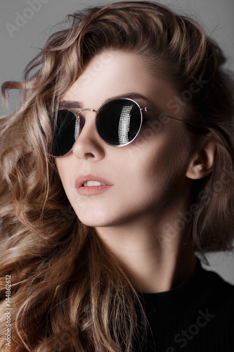 Fashion studio portrait of young sexy woman with perfect skin. Girl in sunglasses.