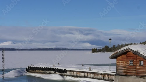 Time lapse of clouds moving over snow covered mountains and a frozen lake
