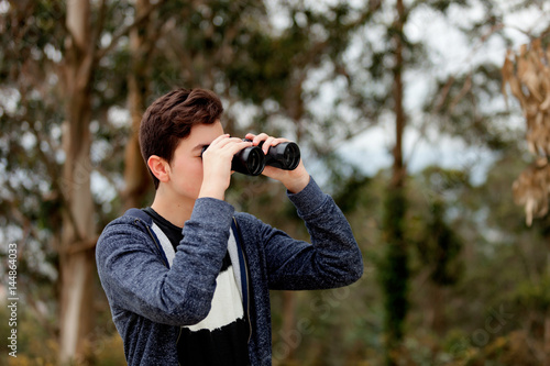 Teenager guy looking with binoculars