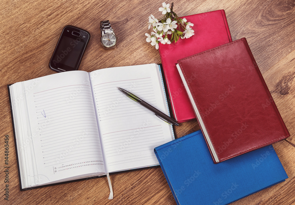 notebooks to write on a wooden background with a clock and a telephone notebooks to write on a wooden background with a clock and a telephone