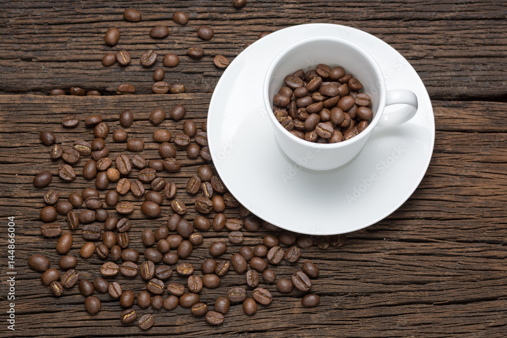 Obraz premium Coffee beans in cup on wooden table