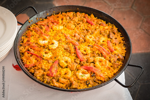 A spanish paella just cooked about to be served at a restaurant somewhere in the spanish coast.