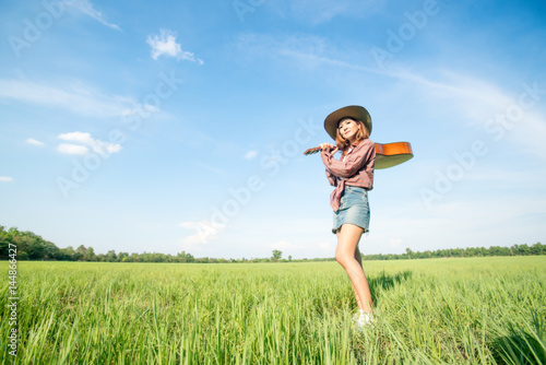 woman with guitar standing in grass field