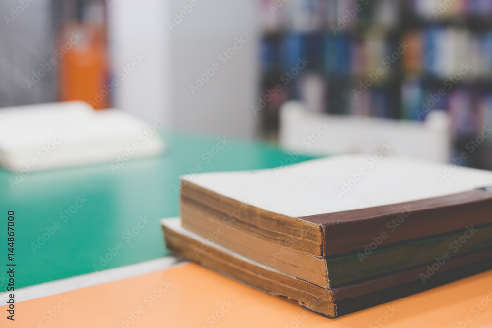 A stack of old books on table with blur book in library, education background A stack of old books on table with blur book in library, education background