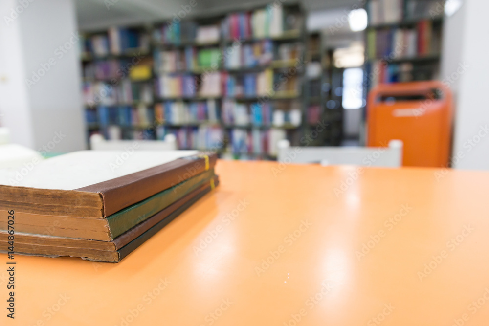 A stack of old books on table with blur book in library, education background A stack of old books on table with blur book in library, education background