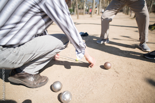 Petanque Spieler beim Messen der Entfernung zwischen den Kugeln photo