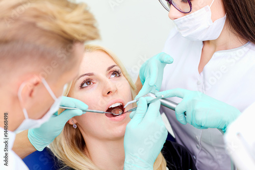 Two dentists treat their teeth to  visitor in dental office.
