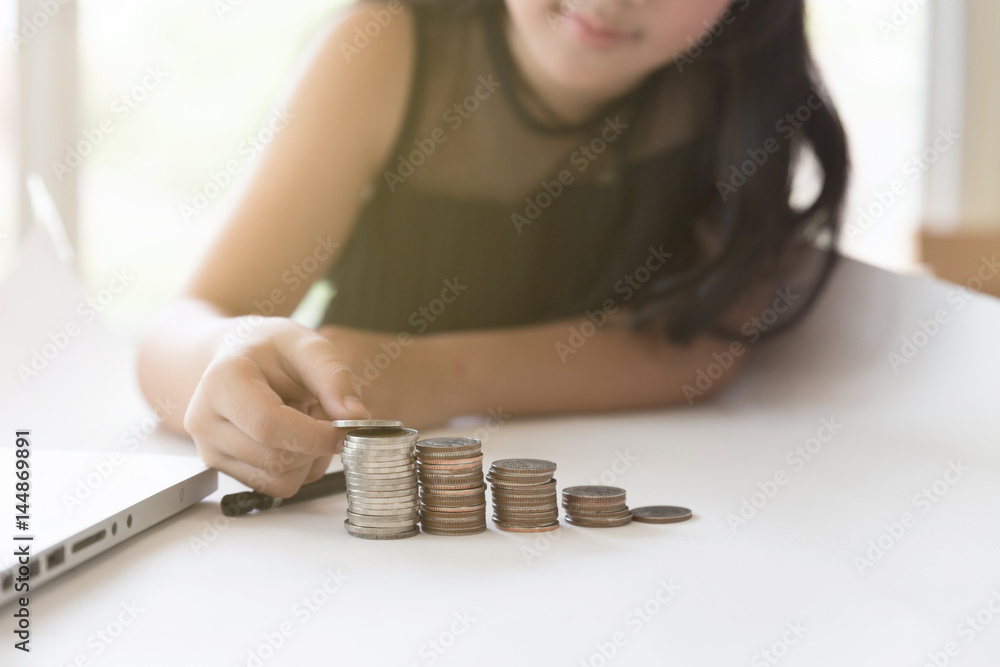 little asian girl put coin to money stack - money saving education concept