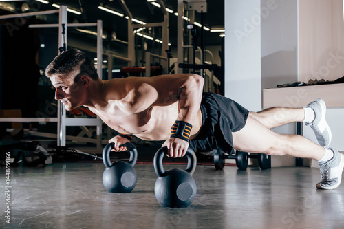 Young muscular man doing pushups with dumbbells