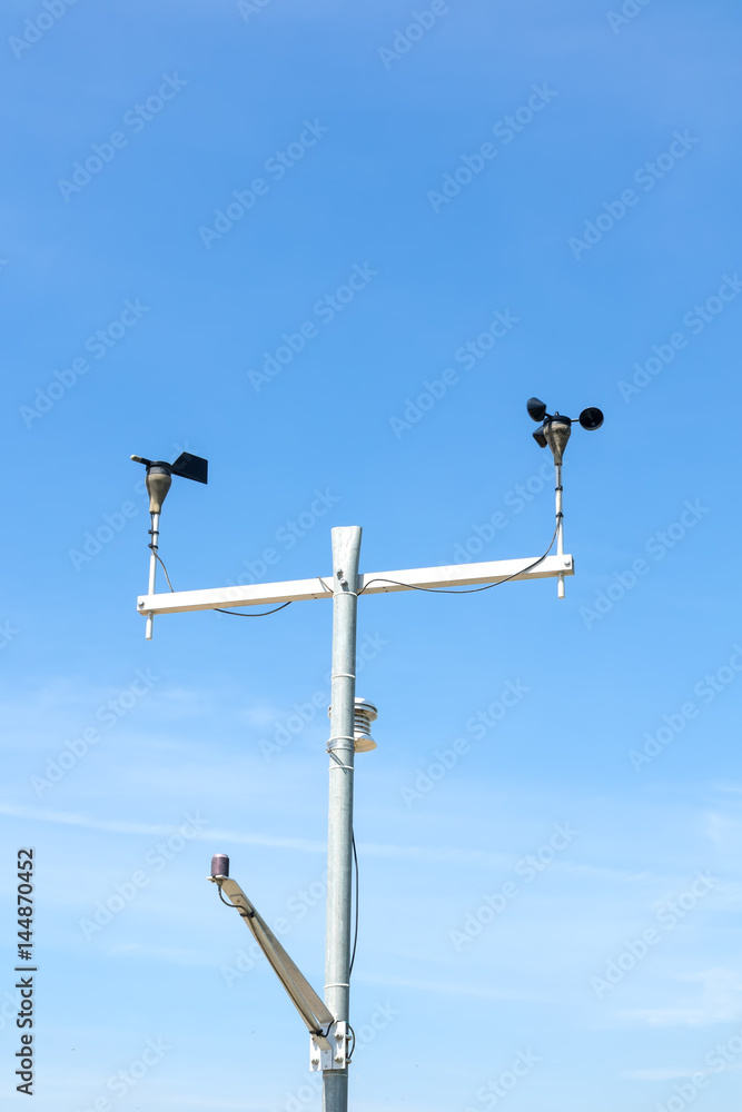 Temperature, anemometer and humidity meteorological instrument on the pole against the clear blue sky.