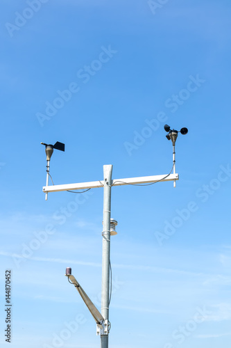 Temperature, anemometer and humidity meteorological instrument on the pole against the clear blue sky.