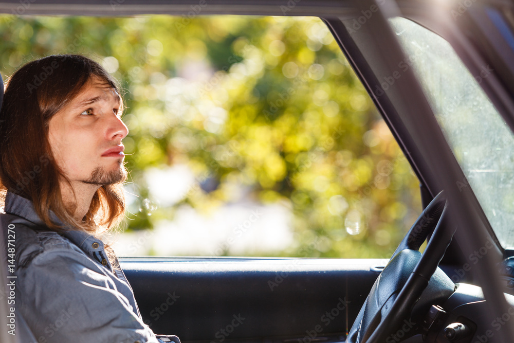 Young man with long hair driving car