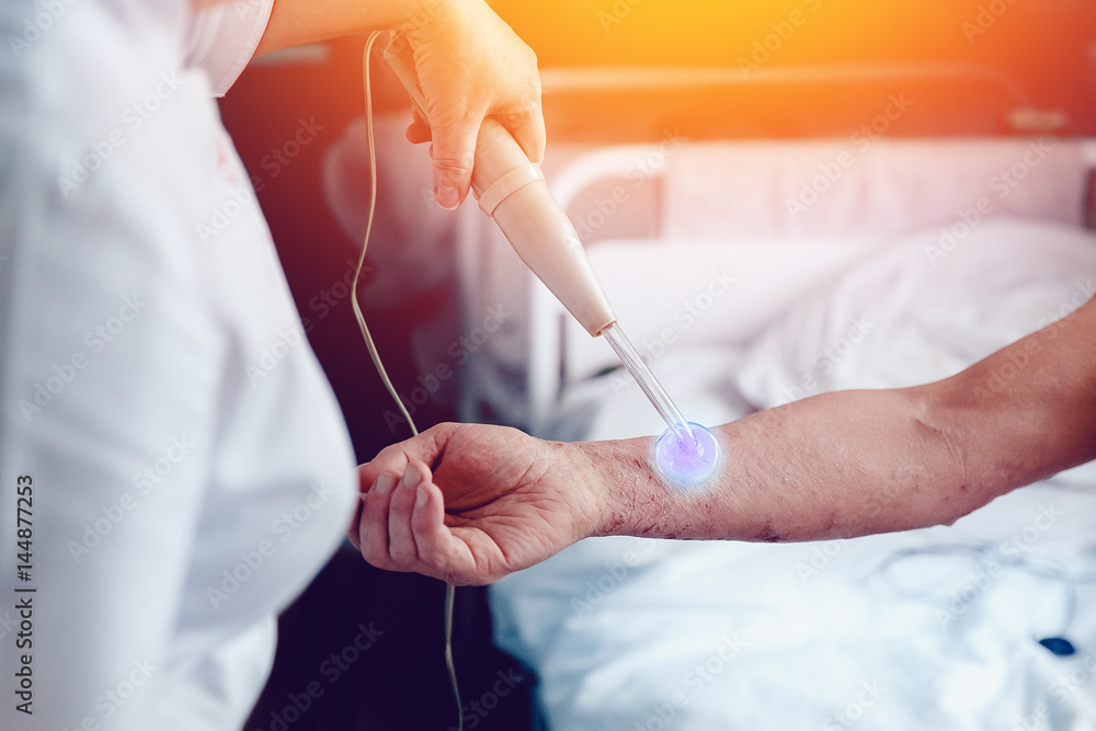 doctor with the phone treats a patient with a skin disease using the Darsonval apparatus for the treatment of dermatitis, apathic, seborrhea, eczema. doctor with the phone treats a patient with a skin disease using the Darsonval apparatus for the treatment of dermatitis, apathic, seborrhea, eczema.