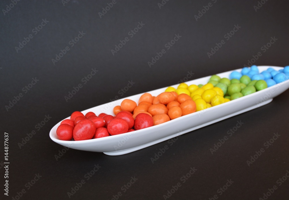 Chocolate lentils in an elongated shape in front of different background colors Chocolate lentils in an elongated shape in front of different background colors