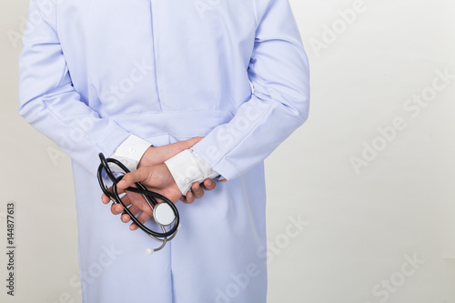 backside view of young doctor, physician holding his stethoscope in hand at clinic or hospital