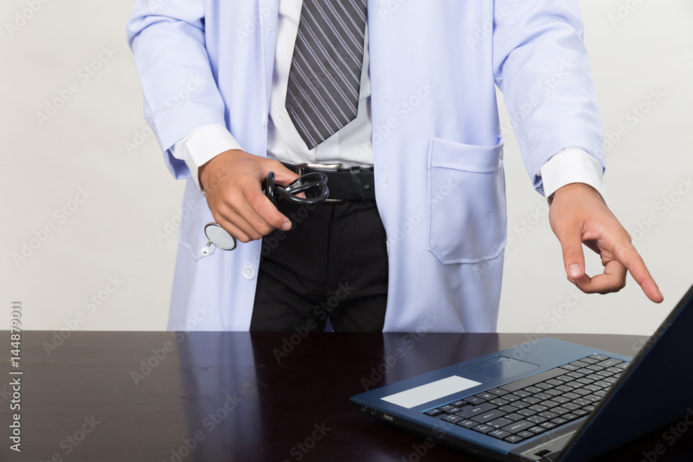 Medicine doctor holding stethoscope and showing medical records on his computer. He is pointing at the screen in clinic - Medical technology concept.
