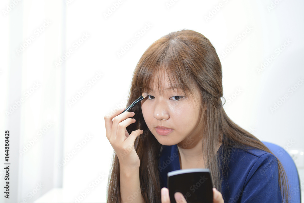 Beautiful asian girl having make up application over the eyes with brush Beautiful asian girl having make up application over the eyes with brush