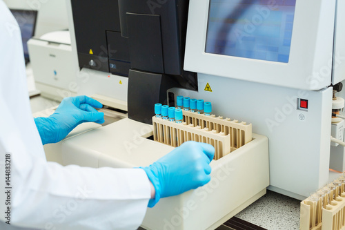 Fotografi Hands of laboratory assistant loading sample tubes for coagulation test analysis