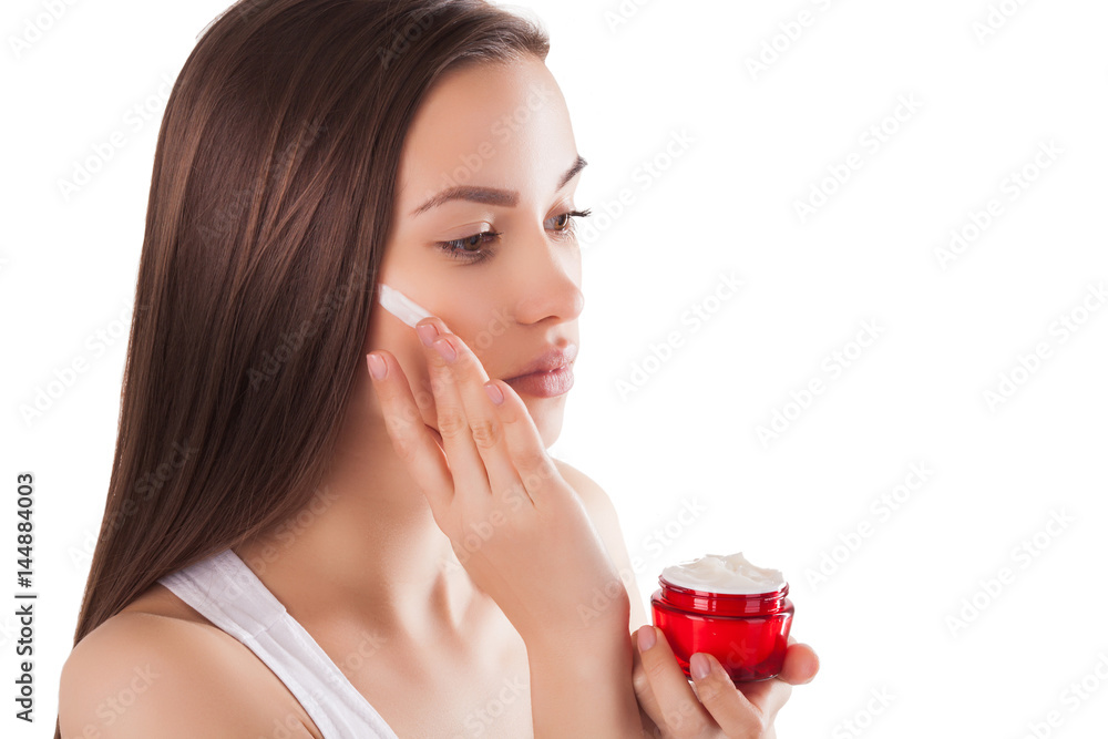 Pretty woman with perfect skin holding a tube with face cream. Young girl with hands on the front. Red jar of cream. Close-up. Isolated background. Beautiful woman wearing a face and hands cream. Pretty woman with perfect skin holding a tube with face cream. Young girl with hands on the front. Red jar of cream. Close-up. Isolated background. Beautiful woman wearing a face and hands cream.