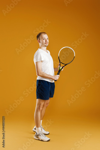 young tennis player plays tennis on yellow background © producer