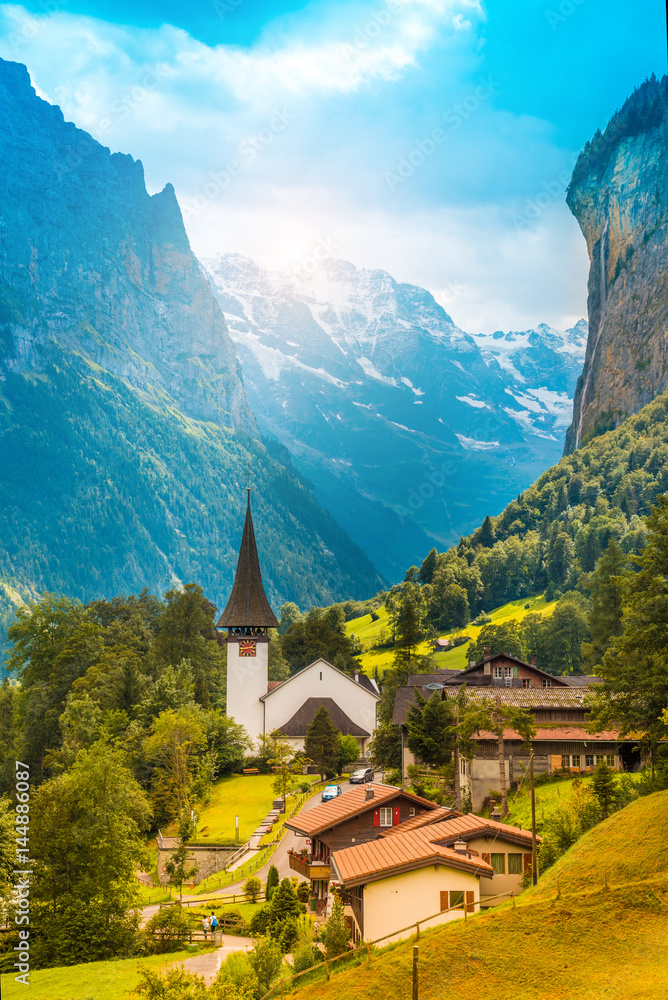 The picturesque landscape with flowers, a waterfall and canyon church in Lauterbrunnen in the Swiss Alps, Switzerland, Europe