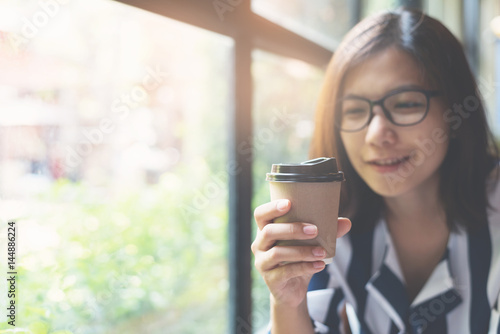 Focus on cup of coffee. Relaxed Asian Woman holding and looking to a cup of coffee. copy space.