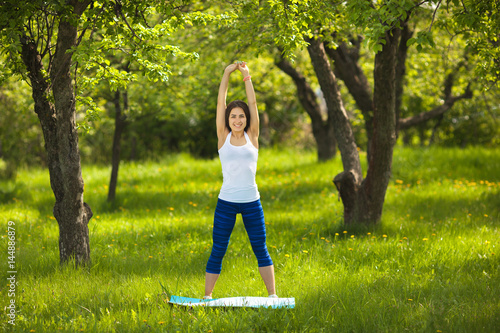 Young girl working out outdoors. Beautiful woman doing pilates, yoga and fitness exercices on nature. photo