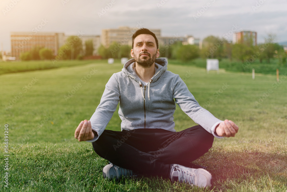 Fototapeta premium Man in sweatsuit doing yoga in urban environment