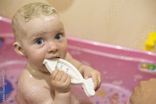 A little one-year-old child sits in a baby bath