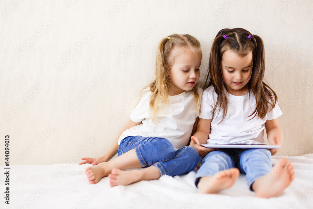 Two little girls using a touch pad family, children, technology and home concept happy little girls with tablet pc computers Two little girls using a touch pad family, children, technology and home concept happy little girls with tablet pc computers
