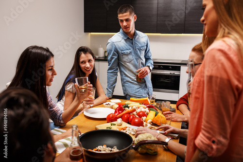 Group of friends in kitchen preparing together vegetarian meal.Home party.