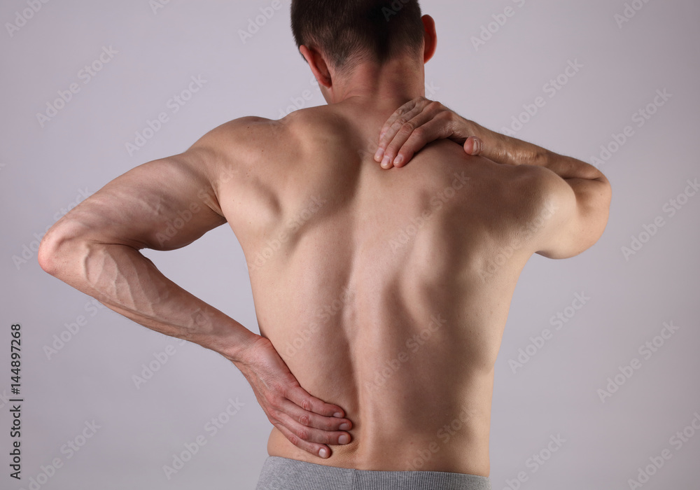 Muscular Man suffering from back and neck pain. Pain relief, chiropractic concept. Sport exercising injury