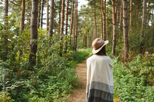 A girl in a poncho and a hat in forest