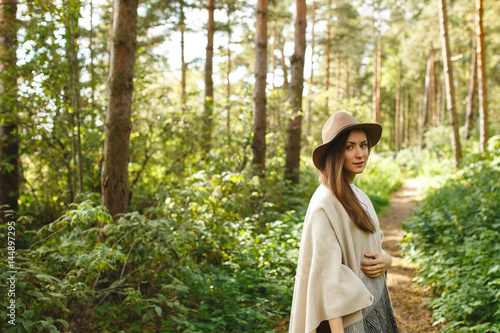 A girl in a poncho and a hat in forest