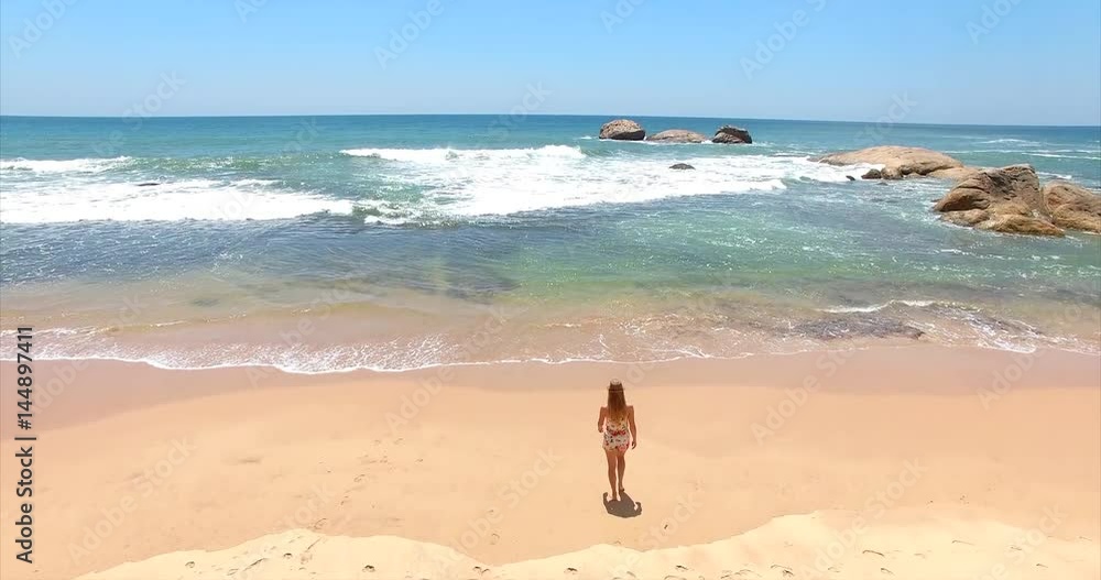 Girl on the beach. Ocean waves. Rocks. Sri Lanka. Aerial footage. Nature background by drone Girl on the beach. Ocean waves. Rocks. Sri Lanka. Aerial footage. Nature background by drone