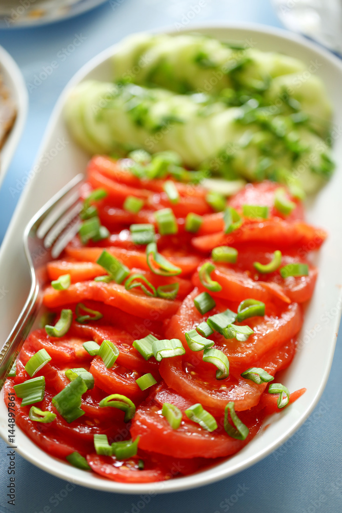 Raw fresh slices tomato and cucumber on white plate