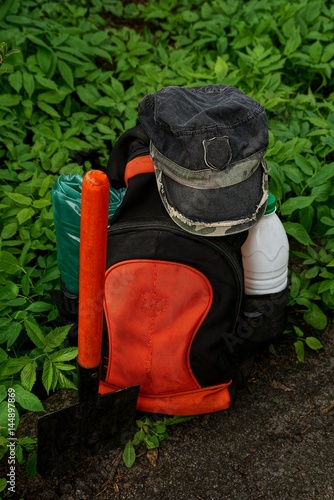рюкзак с вещами и лопатой стоящий на земле с зелёной травой
