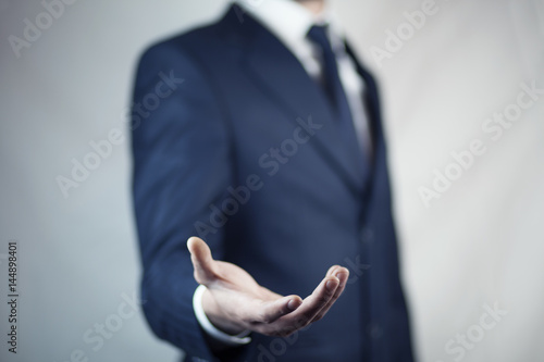 male is standing and shows outstretched hand with open palm