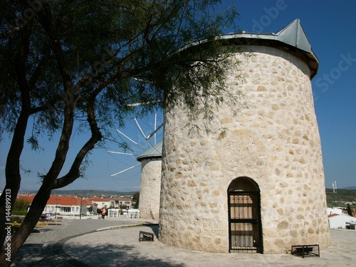 Restaurierte alte griechische Windmühlen mit altem Baum vor blauem Himmel im Sonnenschein. in der Altstadt von Alacati bei Cesme am Ägäischen Meer in der Provinz Izmir in der Türkei photo