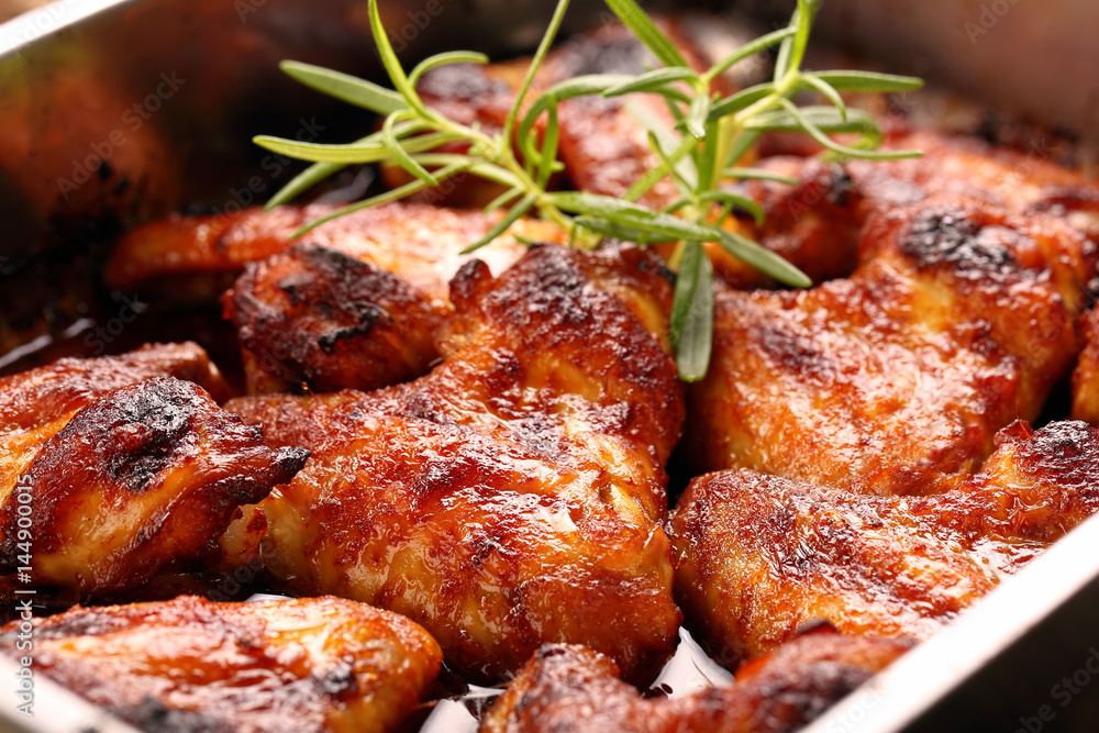 Chicken wings baked in a pan on wooden background