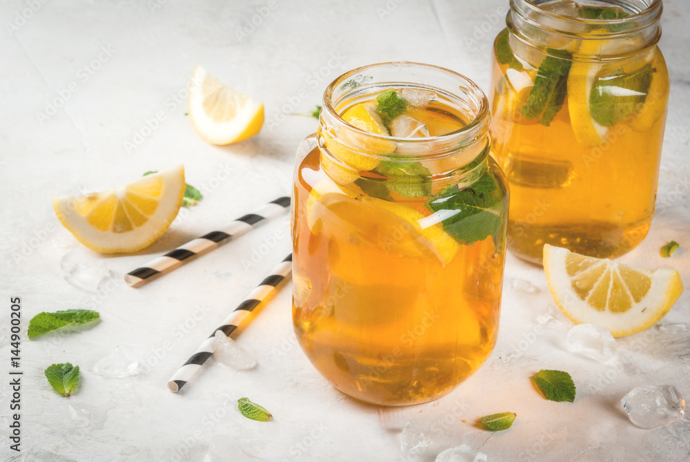 Chilled summer tea with ice, mint and lemon. Two portions in Mason Jars on a white stone table. Copy space Chilled summer tea with ice, mint and lemon. Two portions in Mason Jars on a white stone table. Copy space