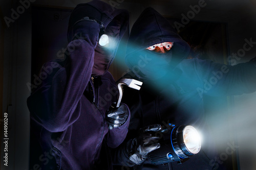zwei Einbrecher mit Taschenlampen sind in ein Gebäude eingedrungen photo