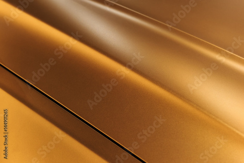 Surface of bronze sport sedan car metal hood, part of vehicle bodywork, steel gradient line pattern, selective focus