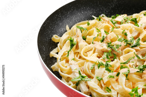 Frying pan with delicious chicken Alfredo on white background