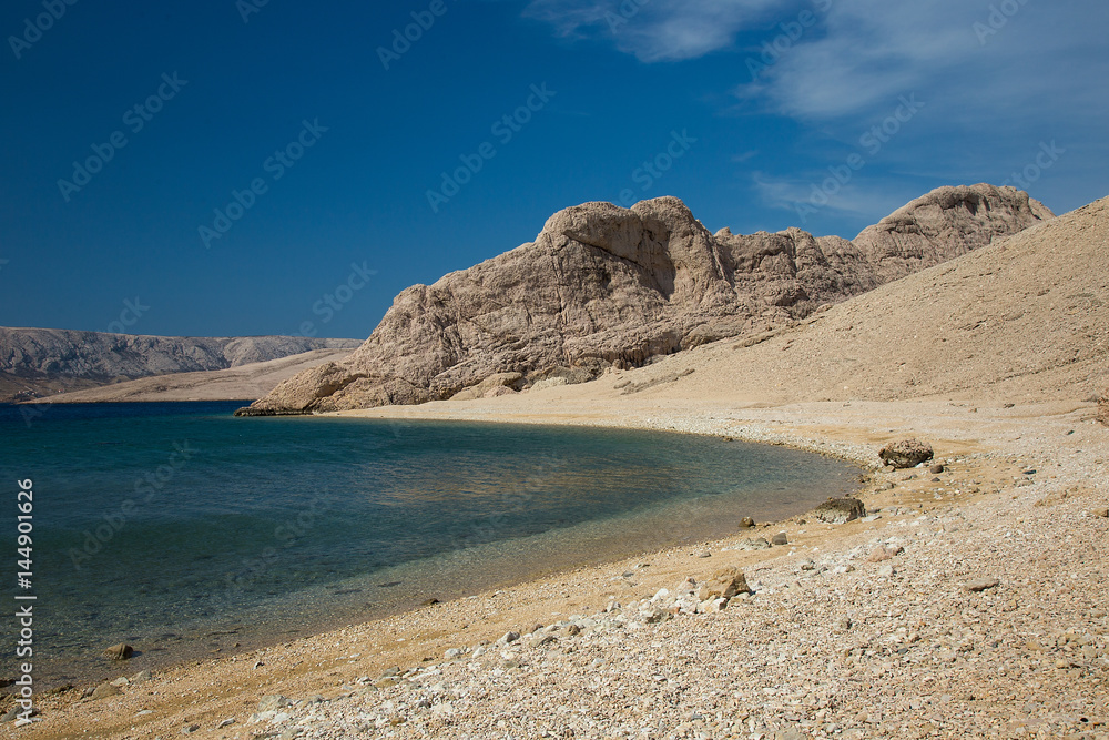 Desert sand beach with big rocks and turquoise blue water - beautiful sea water background