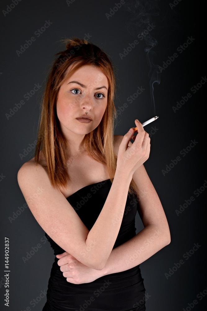 Obraz premium young woman with cigarette, smoking concept on black background