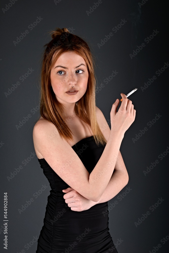 Obraz premium młoda kobieta z papierosem, koncepcja palenia na czarnym tle