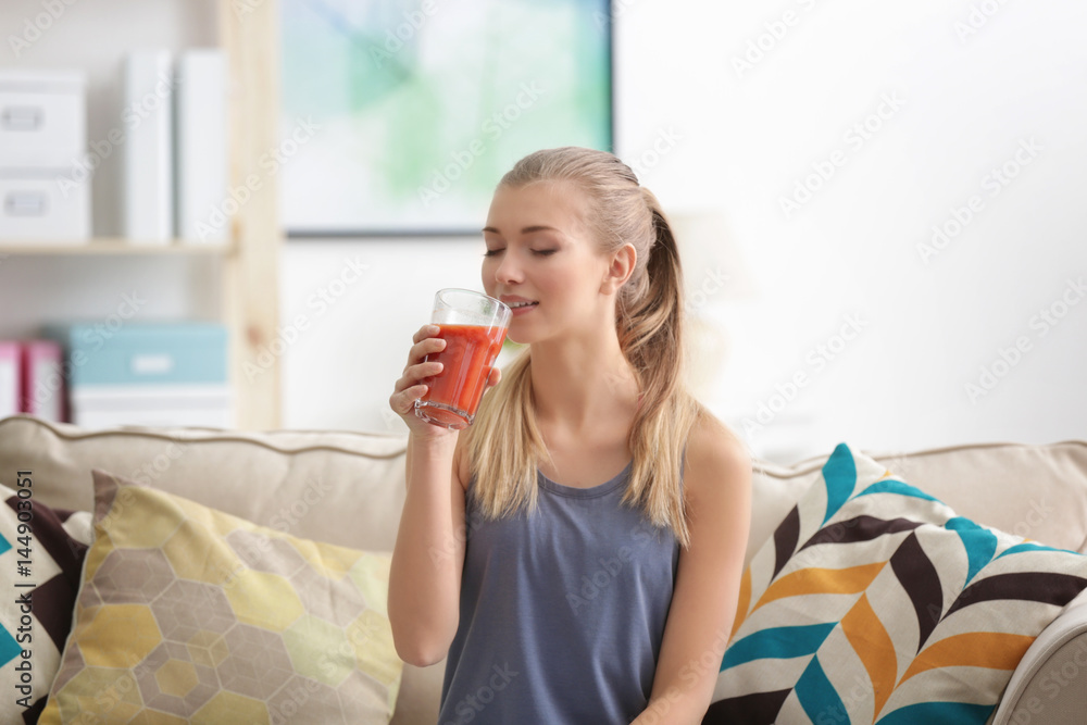 Young woman tasting fresh juice sitting on couch at living room Young woman tasting fresh juice sitting on couch at living room